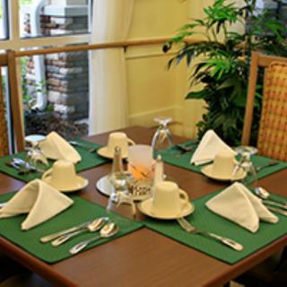 An elegantly set dining table with green placemats and white napkins in a restaurant setting.