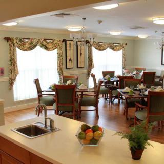 A cozy dining room with elegantly set tables and a view from the kitchen counter.