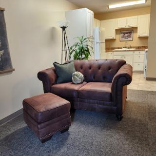A cozy living room setup featuring a stylish sofa and ottoman, complemented by indoor greenery.