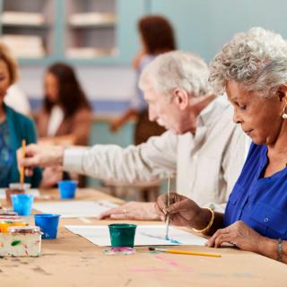 A group of seniors participating in a painting class, engaging in a creative workshop.