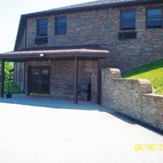 A brick building entrance with an awning and a concrete wall.