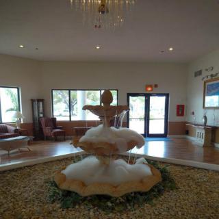 A spacious lobby featuring a central fountain sculpture and a chandelier.