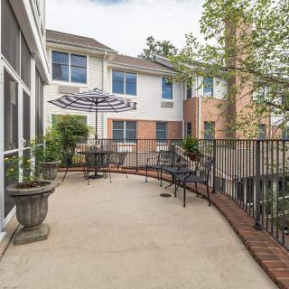 A cozy patio with tables and chairs, featuring large umbrellas and surrounded by a building exterior.