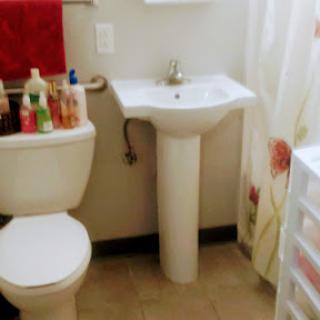 A compact bathroom featuring a sink, toilet, and various personal care products.