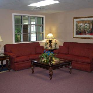 A cozy living room with red sofas and a central coffee table under soft lighting.