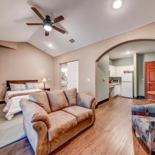 A cozy open floor plan featuring a living area with a couch and a bedroom space, complete with hardwood floors and a ceiling fan.
