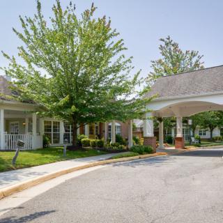 A well-maintained building entrance with a covered driveway and lush green landscaping.
