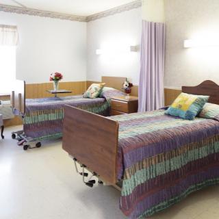 A well-organized hospital room with two beds and privacy curtains.