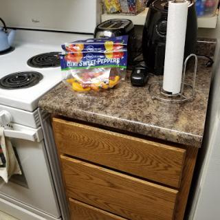 A cozy kitchen setup featuring a stove, countertop with fruit, and storage drawers.
