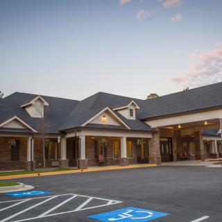 A modern clinic building with a parking lot in front.