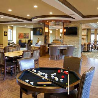 A modern recreational room featuring a pool table and various seating areas.