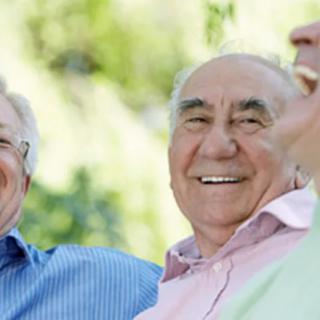 A group of elderly men smiling and enjoying their time outdoors.