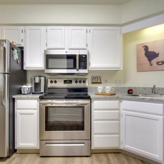 A modern kitchen featuring stainless steel appliances and white cabinetry.
