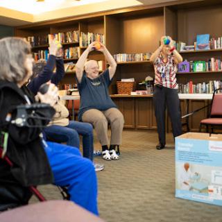 Seniors participating in a group exercise session, focusing on movement and wellness in a library setting.