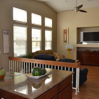 A modern living room with a television, large windows, and comfortable seating.