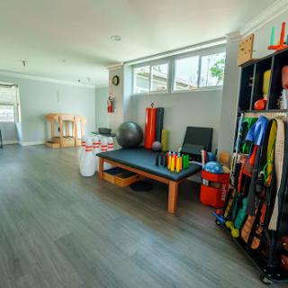 A well-lit therapy space designed for exercise and fitness activities, featuring colorful equipment and a spacious layout.