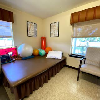 A cozy therapy room equipped with exercise balls, a bed, and a comfortable chair.