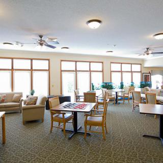 A spacious lounge with tables, chairs, and large windows.