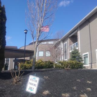 A view of a building with an American flag flying and landscaped grounds.