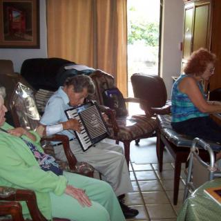 A group of seniors gathered indoors, with one person playing the accordion.