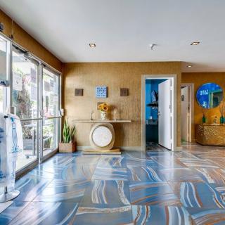 A modern lobby featuring artistic flooring and stylish decor with large glass doors allowing natural light.