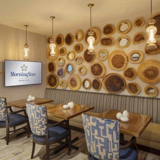 A stylish restaurant interior featuring wooden wall art and modern seating.