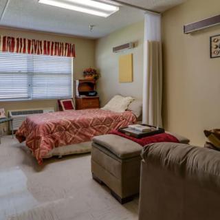 A cozy bedroom with a bed, chair, and large window.