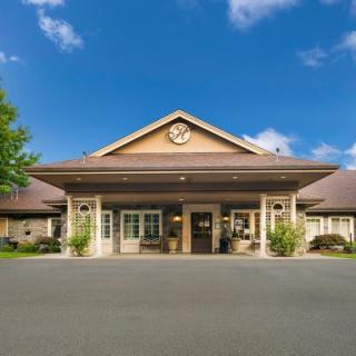 A welcoming building facade with a central clock and landscaped entrance under a clear blue sky.