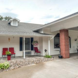 A cozy house with a front porch featuring red chairs, a garage, and a driveway.
