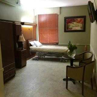 A hospital room with a single bed and comfortable seating.