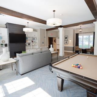 A stylish and spacious living room featuring a pool table, modern furnishings, and ample natural light.