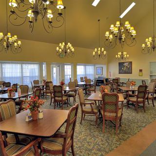 A spacious dining room with elegant chandeliers and neatly arranged tables and chairs.