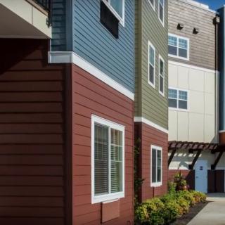Modern apartment building exterior with colorful siding and multiple windows.