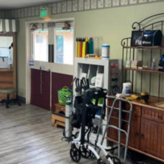 A healthcare facility room with medical equipment and supplies, including a wheelchair and walker.