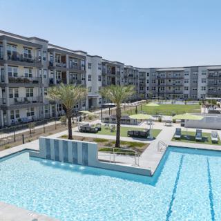 A modern residential complex featuring a swimming pool and landscaped outdoor areas.