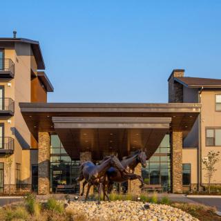 A modern building entrance featuring a prominent horse sculpture.