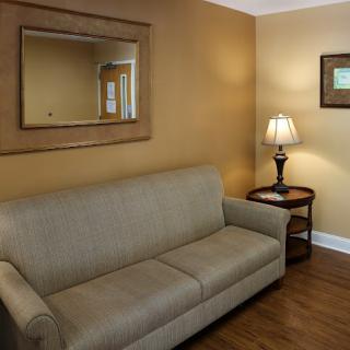 A cozy living room featuring a beige sofa, a decorative mirror, and a warm lamp.