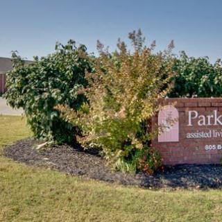 A landscaped area with bushes and a brick sign displaying text.