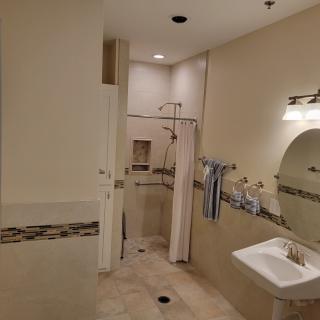 A spacious bathroom featuring a walk-in shower, sink with a mirror, and neatly arranged towels.