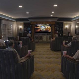 A cozy home theater room with people seated and watching a movie on the screen.