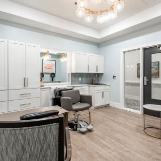 A modern hair salon interior featuring sleek white cabinetry, stylish chairs, and elegant lighting.