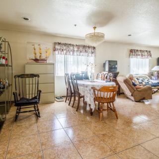 A cozy living and dining area with wooden furniture, large windows, and tiled flooring.