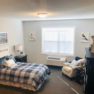 A cozy bedroom with a plaid bedspread, an armchair, and wall decor.