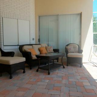A cozy patio setup with rattan furniture and cushioned seating.