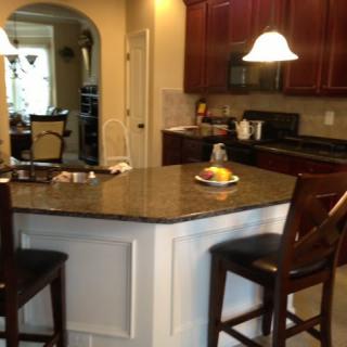 A modern kitchen featuring a central island with bar stools and overhead lighting.