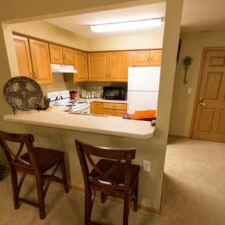 A cozy kitchen with wooden cabinets, a counter, and two chairs.