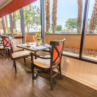 A bright restaurant dining area with a set table by large windows.