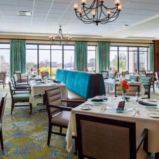 An elegant dining room with neatly arranged tables and chandeliers, offering a formal setting with large windows providing ample natural light.