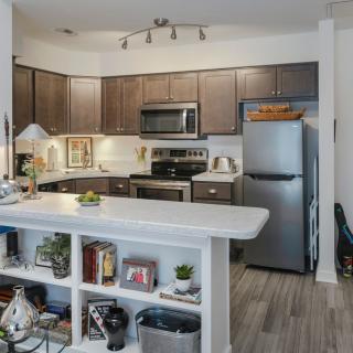A modern kitchen with wooden cabinets, stainless steel appliances, and an open shelf island.