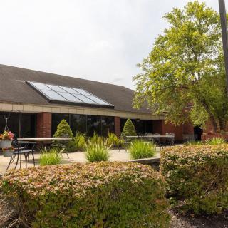 A brick building with solar panels on the roof, surrounded by a landscaped garden.